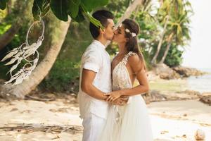 jovem e lindo casal está comemorando casamento na praia foto
