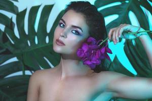 mulher jovem e bonita com pele lisa perfeita está segurando flores de orquídea foto