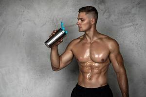 homem musculoso bebendo whey protein ou outro suplemento esportivo foto