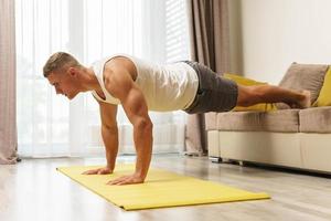 homem musculoso fazendo flexões durante treino em casa foto