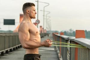 homem musculoso durante treino com um elástico de resistência em uma rua foto