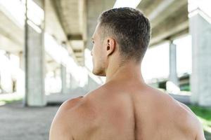 homem musculoso debaixo de uma ponte durante seu treino de rua fitness foto