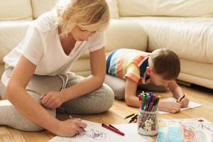 feliz mãe e filho estão desenhando juntos em casa foto