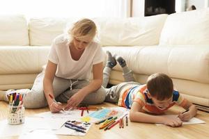 mãe e filho estão desenhando juntos em casa foto