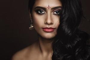 retrato de mulher indiana com bela maquiagem e penteado em fundo marrom foto