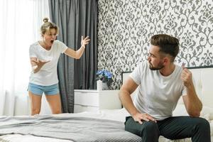 mulher irritada e homem triste. casal conflitante no quarto em casa. foto