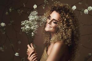 linda jovem com penteado afro e maquiagem linda com muitas flores brancas foto