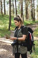 alpinista feminina com mochila grande usando mapa para orientação na floresta foto