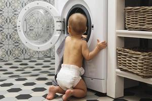 menino bonito está olhando para dentro da máquina de lavar foto