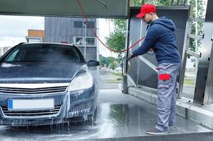 trabalhador de lavagem de carros está lavando o carro do cliente foto