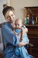 jovem linda mãe com seu bebezinho embrulhado no pano azul foto