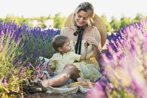 jovem mulher com seu filho bonitinho em um campo de lavanda foto