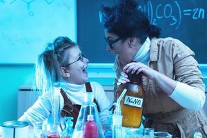 professora e garotinha durante aula de química misturando produtos químicos em um laboratório foto