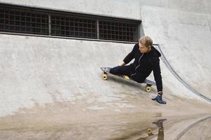 jovem deficiente com um longboard em um skatepark foto
