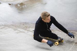 cara deficiente motivado com um longboard no skatepark foto