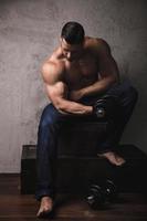 fisiculturista enorme fazendo exercício de rosca bíceps com o haltere foto