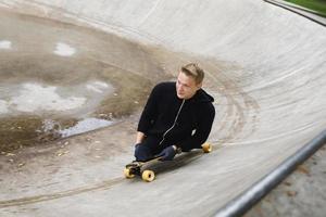 cara deficiente motivado com um longboard no skatepark foto