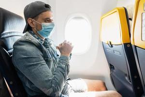 homem usando máscara de prevenção durante um voo dentro de um avião foto