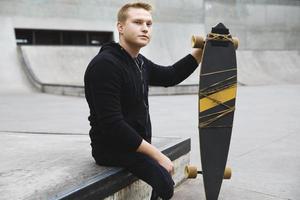 jovem deficiente com um longboard em um skatepark foto