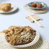 mie goreng ala mie gacoan, macarrão frito com cobertura de frango desfiado. servido com bolinho frito. foto