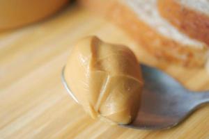 close-up de manteiga de amendoim na colher na mesa foto