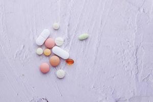 vista superior de muitos comprimidos coloridos e cápsulas derramando em branco foto
