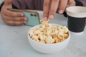 mulheres jovens comendo pipoca e segurando um telefone inteligente foto