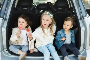 crianças sentadas no porta-malas de um carro antes de uma viagem foto