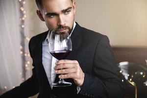 homem barbudo bonito com um copo de vinho tinto foto