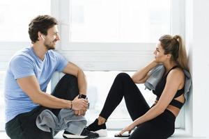 homem e mulher descansando após treino na academia foto