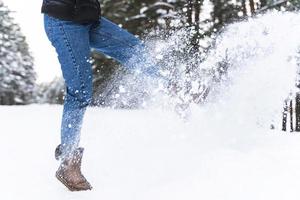 mulher vestindo botas de pele de carneiro está chutando neve foto