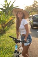 mulher com uma bicicleta na estrada estreita foto