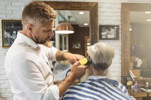 cabeleireiro fazendo corte de cabelo elegante para um velho bonito foto