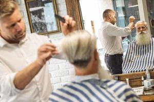 cabeleireiro fazendo corte de cabelo elegante para um velho bonito foto