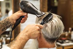 cabeleireiro fazendo corte de cabelo elegante para um velho bonito foto