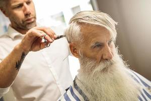 cabeleireiro fazendo corte de cabelo elegante para um velho bonito foto