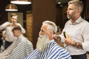 cabeleireiro fazendo corte de cabelo elegante para um velho bonito foto