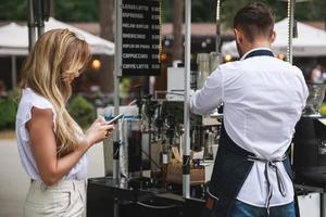 homem barista fazendo café para o cliente em sua cafeteria foto