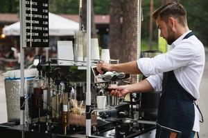 homem barista bonito durante o trabalho em sua cafeteria de rua foto