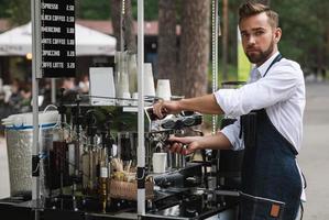 homem barista bonito durante o trabalho em sua cafeteria de rua foto