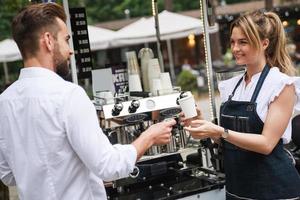 linda mulher barista vendendo café para o cliente foto