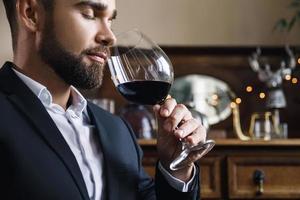 homem barbudo bonito com um copo de vinho tinto foto