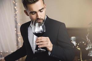 homem barbudo bonito com um copo de vinho tinto foto