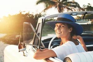 mulher jovem feliz e carro conversível retrô foto