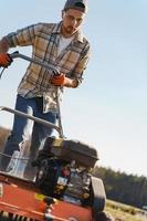 homem usando máquina aeradora para escarificação e aeração de gramado ou prado foto