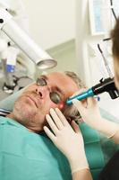 homem de meia idade durante tratamento a laser em uma clínica de estética médica foto