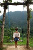 mulher na corda balança com bela vista em terraços de arroz em bali. foto