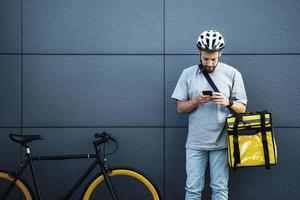 correio expresso de entrega de comida com saco isolado, olhando para o telefone. foto