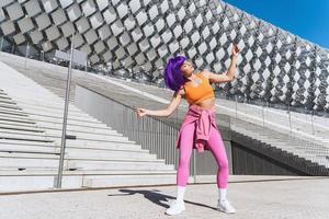 dançarina ativa despreocupada vestindo roupas esportivas coloridas se divertindo na rua foto