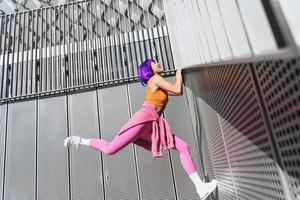 mulher feliz vestindo roupas esportivas coloridas subindo na parede foto